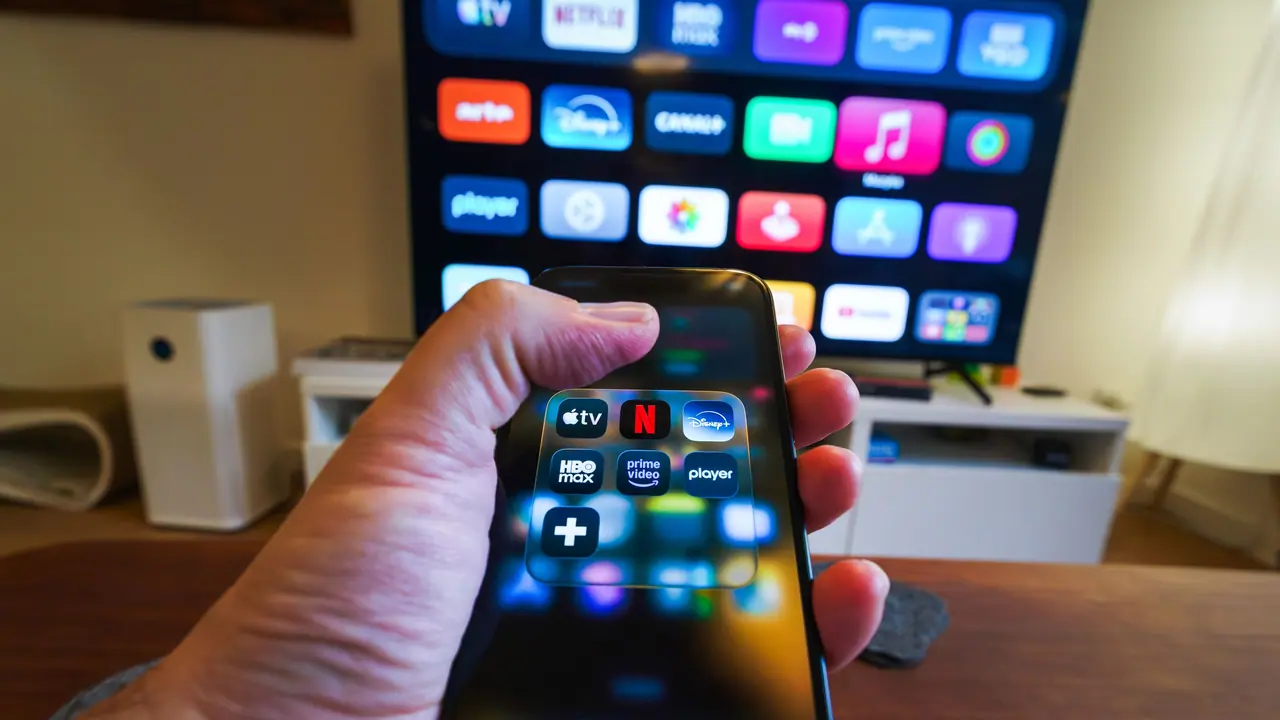 Hands holding a streaming device remote while setting up IPTV on television